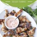 Garlic and herb wings on a white platter with a small white bowl of sun dried tomato mayo