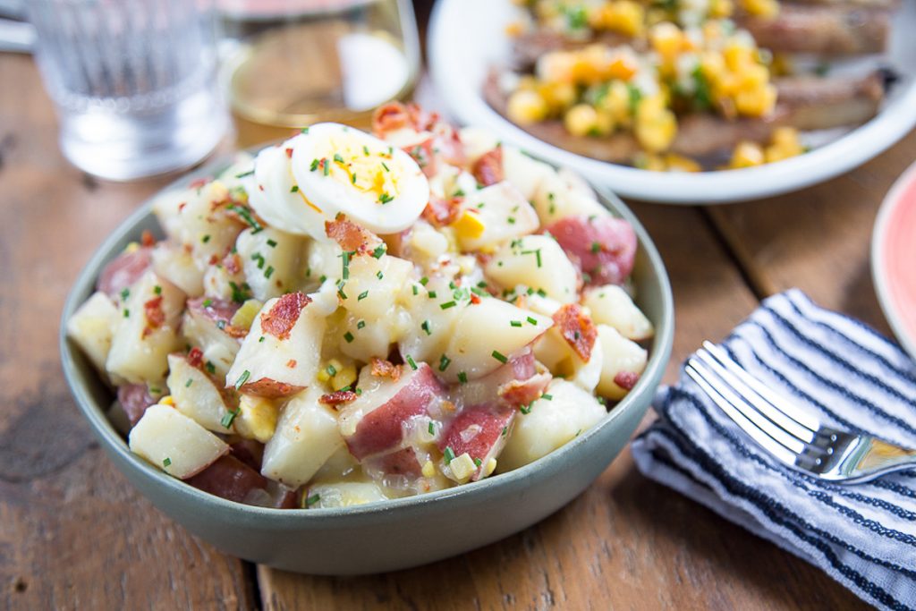 german potato salad in a green bowl on a dinner table