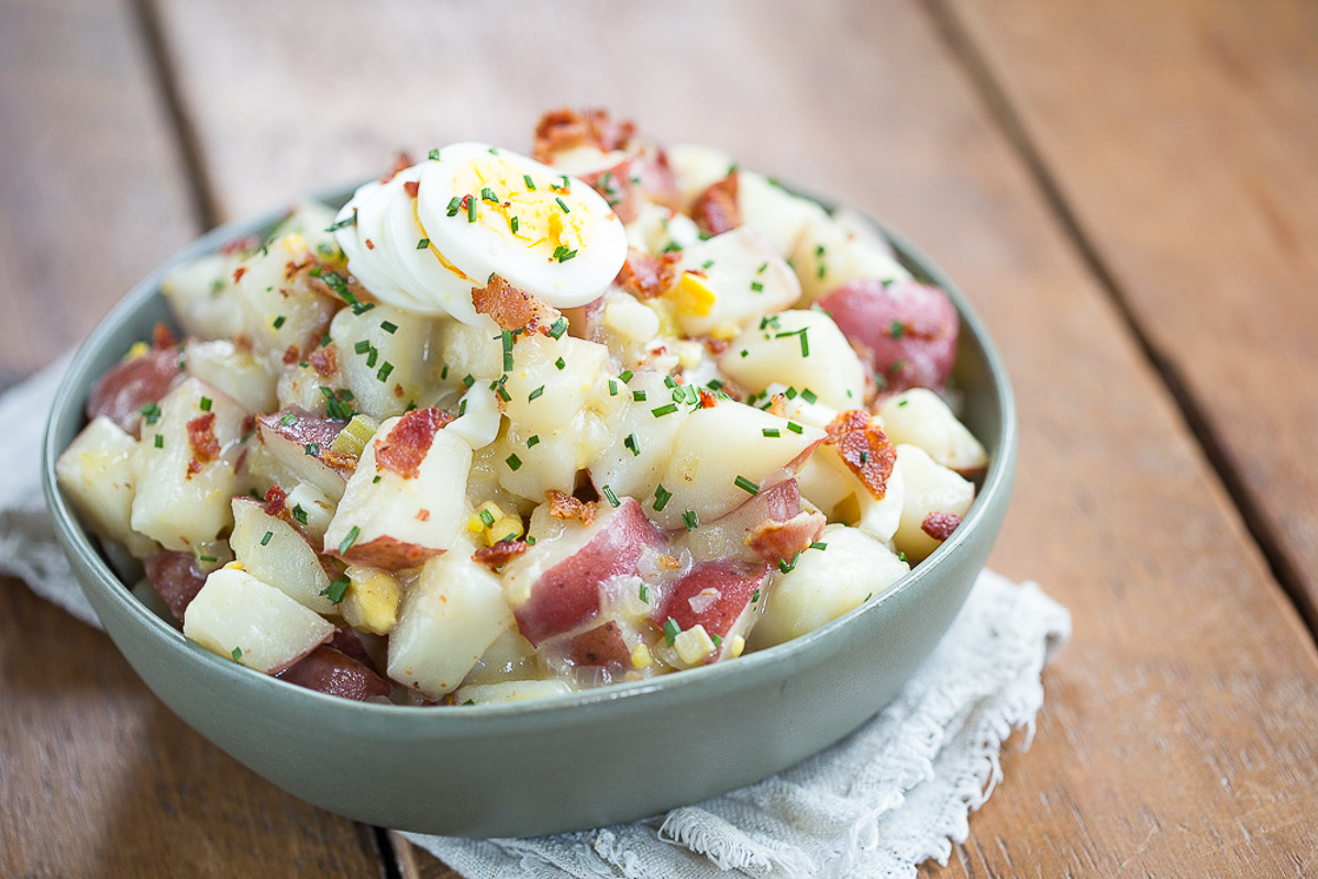 German potato salad in a green bowl on a wood table