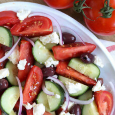 Greek salad with feta on a white platter.