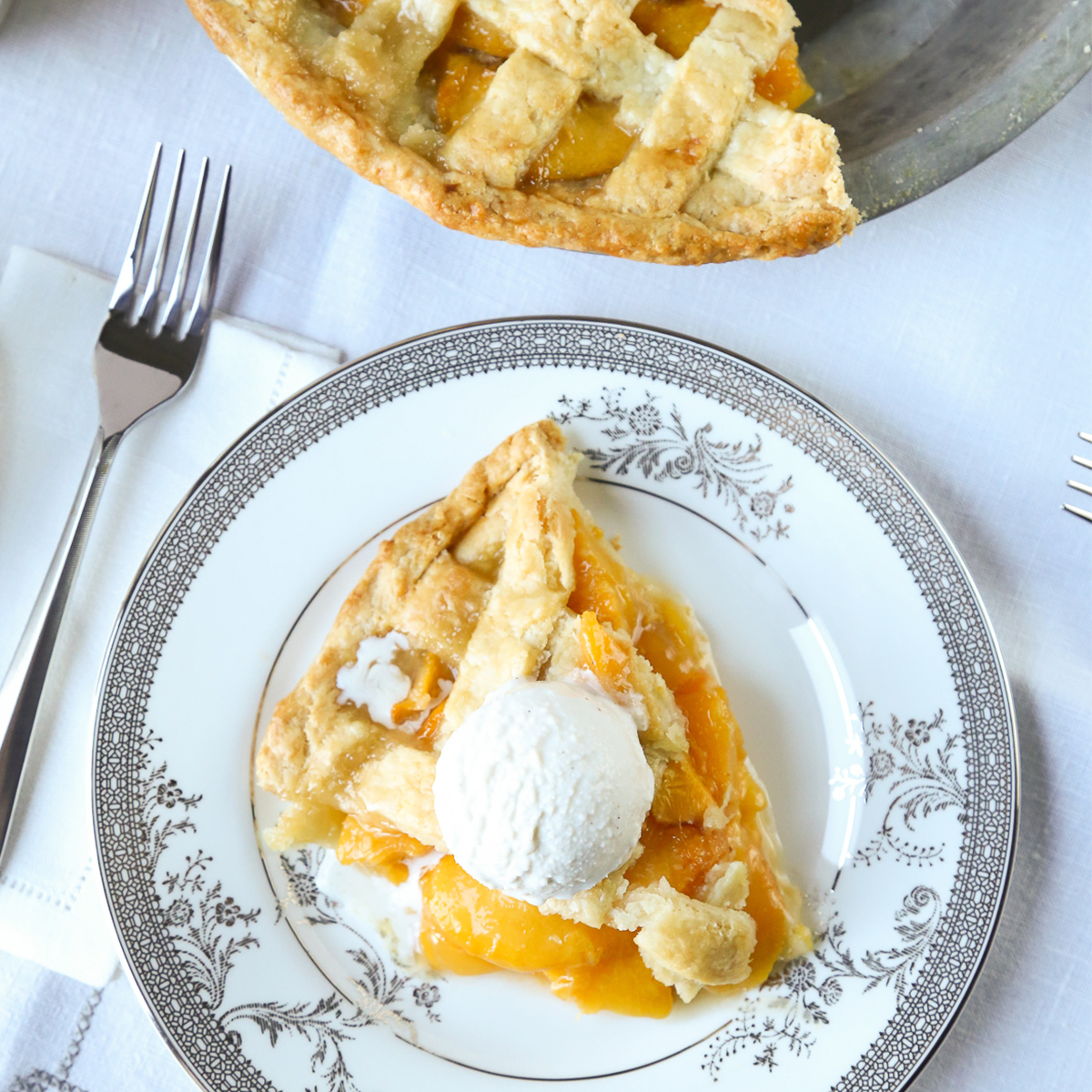slice of peach pie on a piece of fine china with a fork on the side