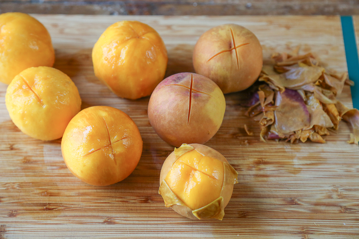 peaches on a cutting board with the peels coming off