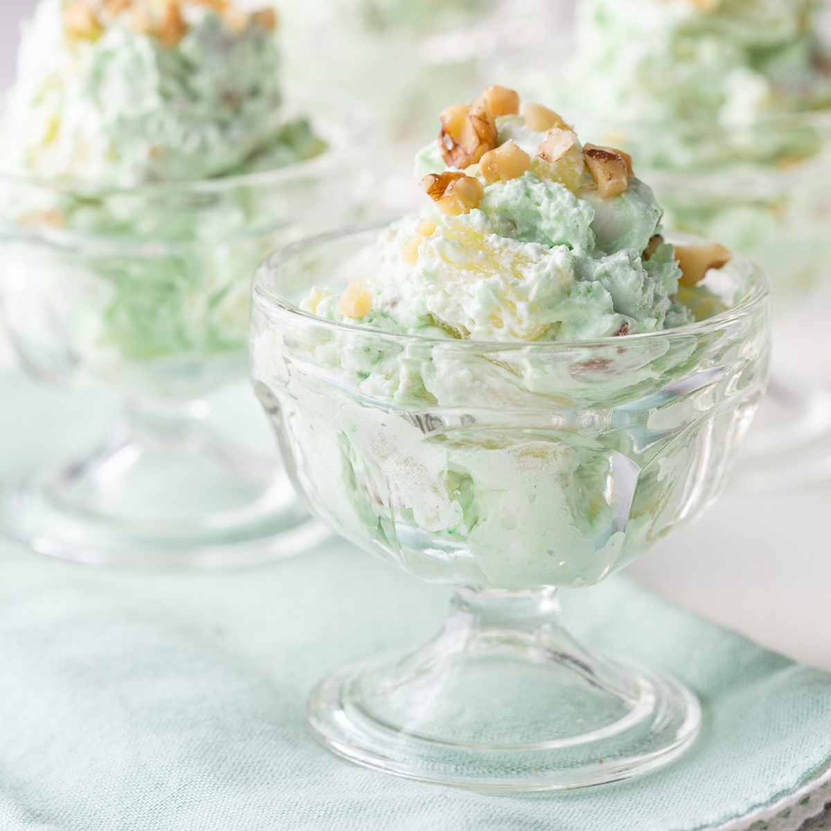 glass parfait dishes filled with pistachio salad, topped with chopped walnuts