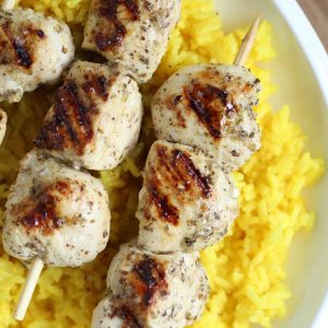 greek chicken kabobs on top of golden rice