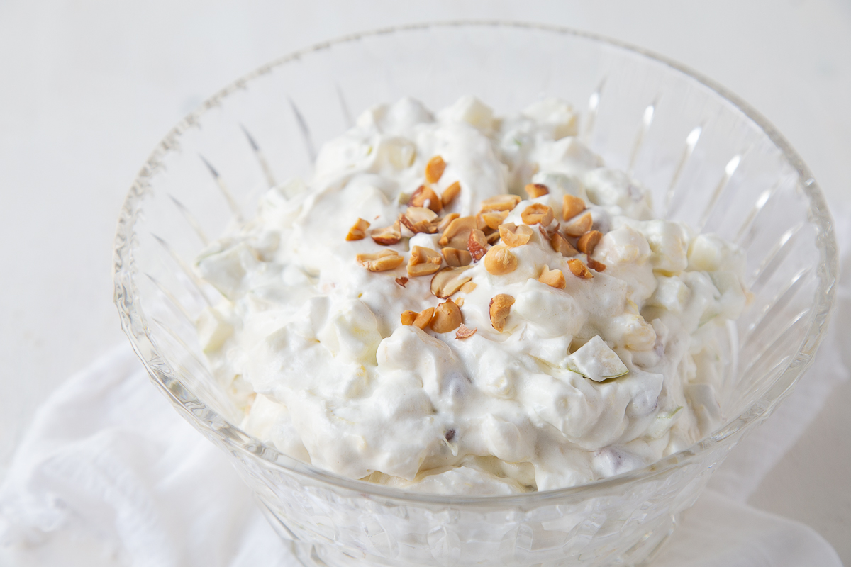 taffy apple salad topped with nuts in a glass bowl