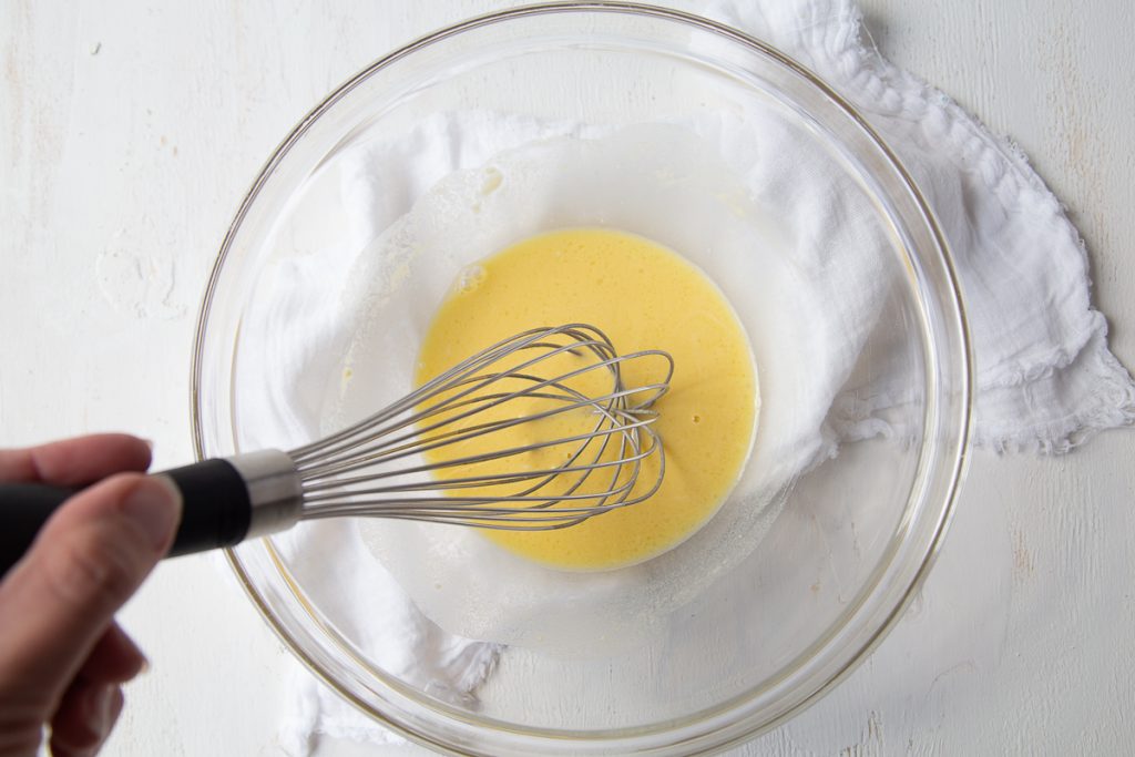 hand whisking egg, vinegar, and flour in a glass bowl