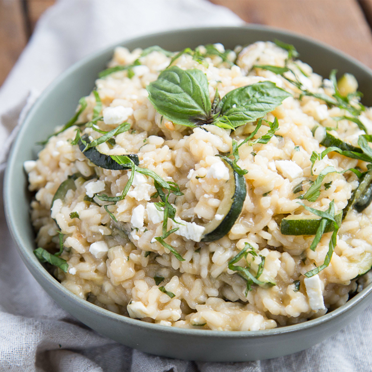 zucchini risotto in a green bowl on a tea towel