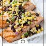 grilled salmon topped with corn salsa on a white platter