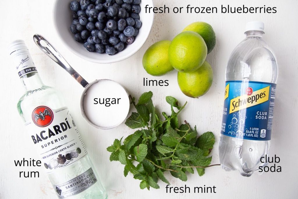 ingredients for a blueberry mojito on a white table