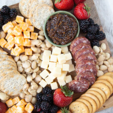 selection of cheese, crackers, fruit, and nuts on a wooden board