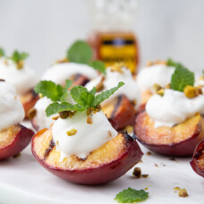 grilled peaches with whipped cream and mint on a white platter