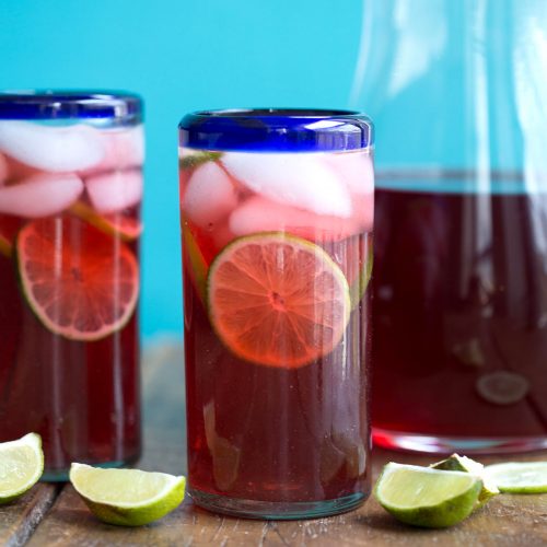 glass of hibiscus iced tea with limes