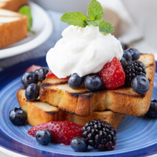 grilled pound cake with berries and whipped cream on a blue plate