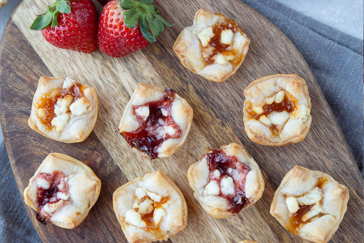 puff pastry appetizers on a wooden board with strawberries for garnish