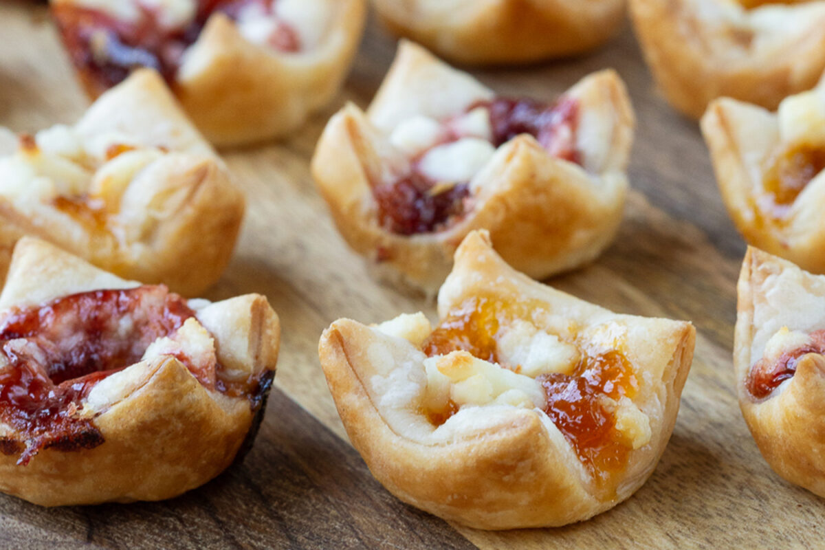 puff pastry bites with goat cheese and jam on a wooden board
