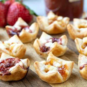 puff pastry appetizers with goat cheese and jam on a wooden board