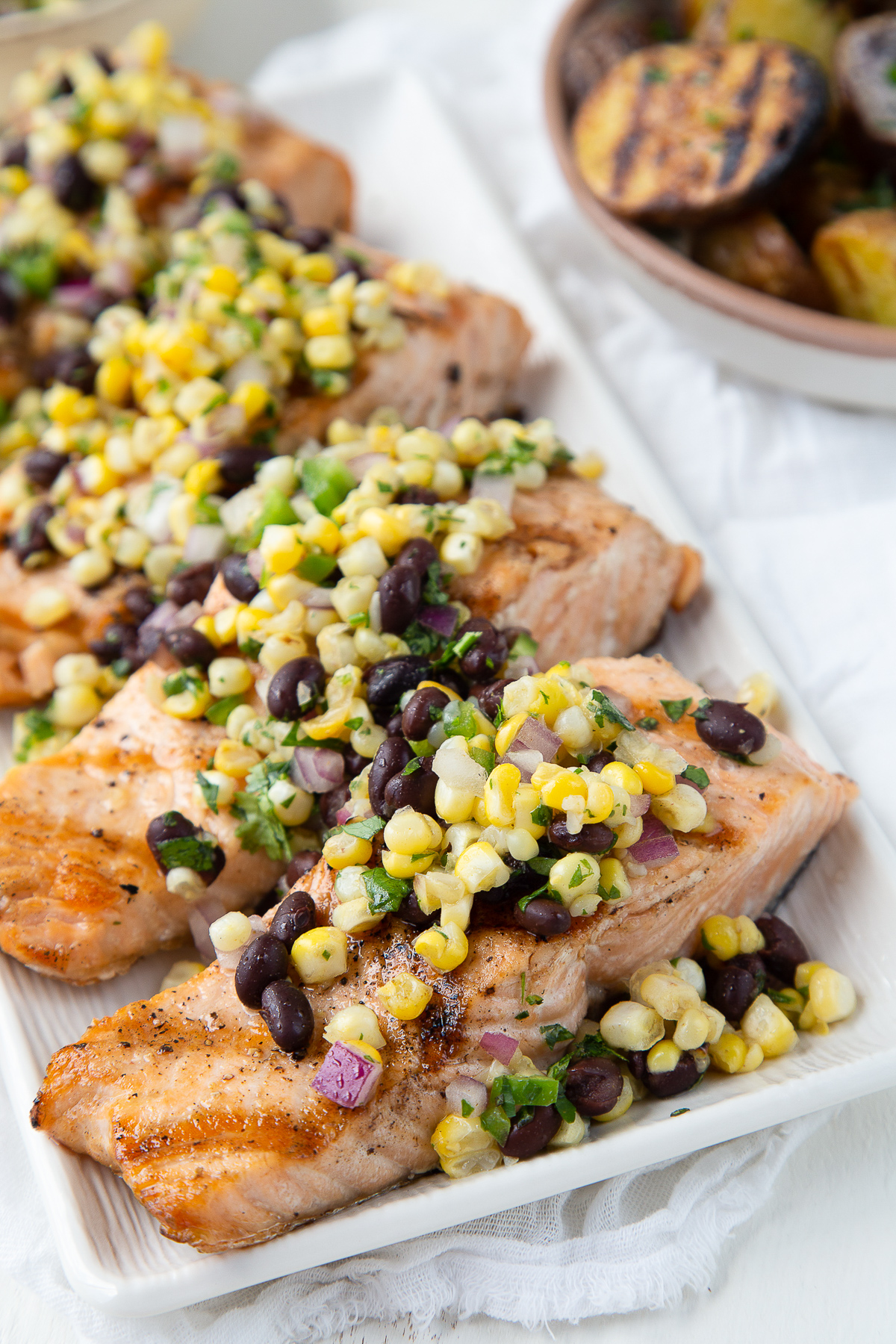 grilled salmon with corn salsa on a white platter