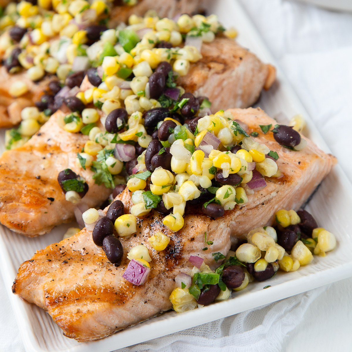 grilled salmon with corn salsa on a white platter