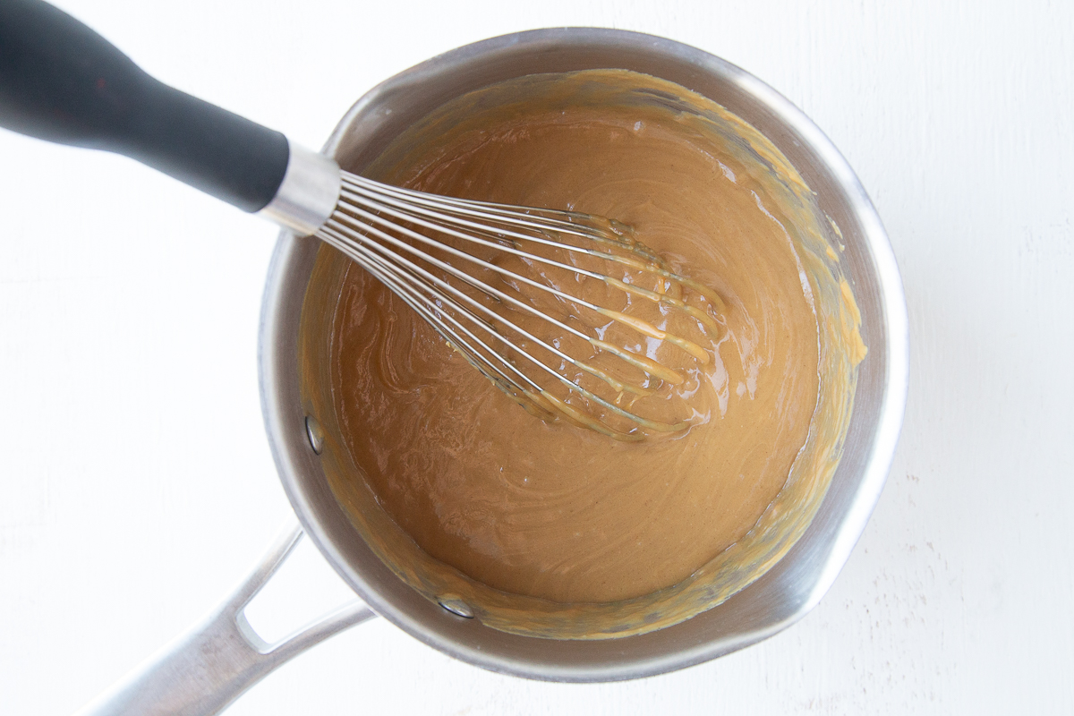 peanut butter mixture in a saucepan with a whisk
