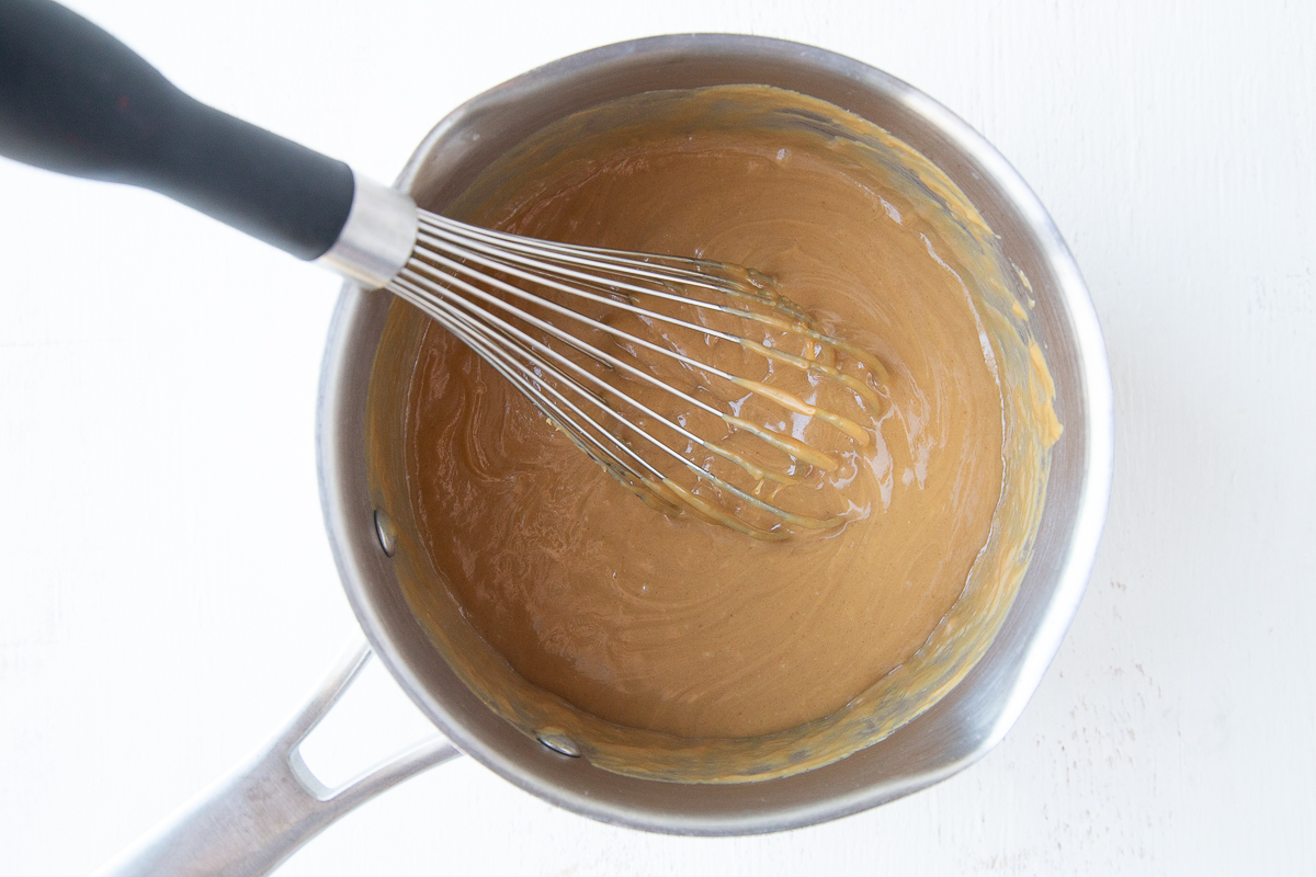 peanut butter mixture in a saucepan with a whisk