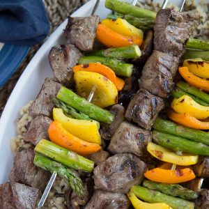 beef and veggie kabobs on a white platter