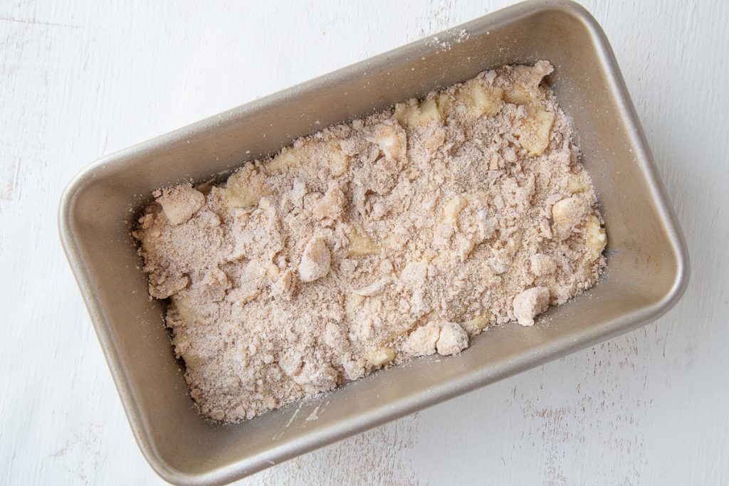 uncooked apple bread with streusel halfway filled in a loaf pan