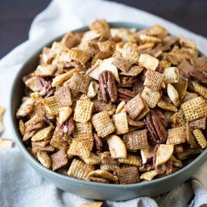 apple cinnamon chex mix in a green bowl on a cream tea towel