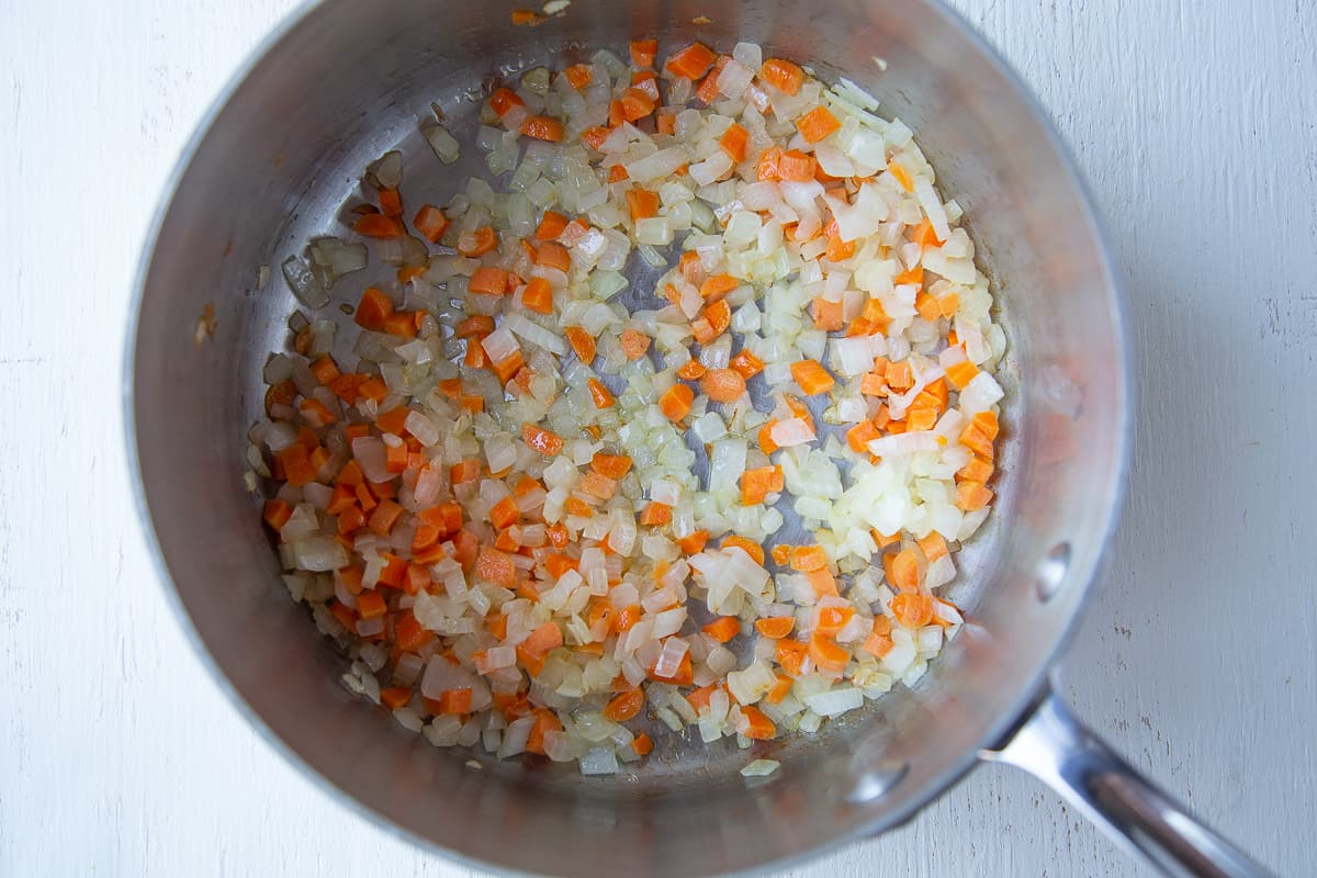 carrots and onions sauteeing in a pot