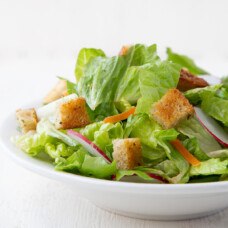 bowl of leafy green salad with croutons on top