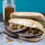 Italian beef sandwich on a soft roll, sitting on white parchment paper.