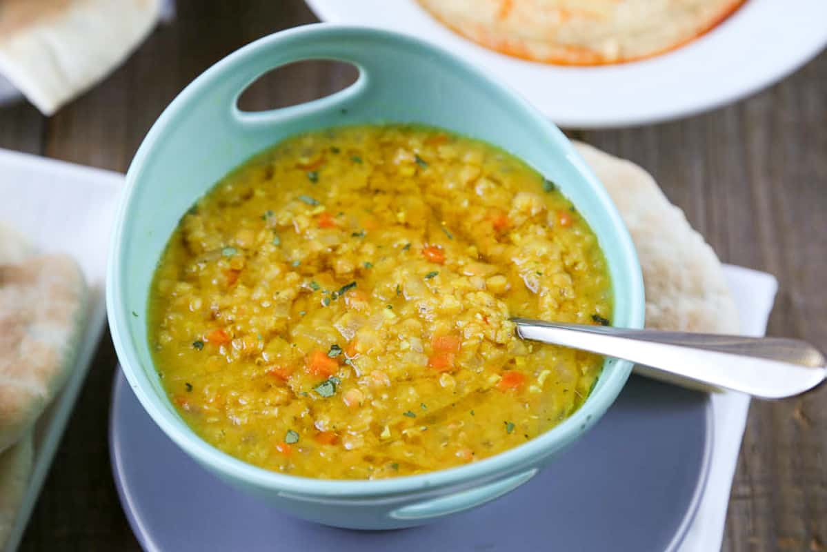 lebanese lemon lentil soup with a spoon in it, in a turquoise bowl.