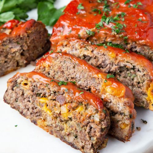 slices of bacon cheddar cheeseburger meatloaf on a white serving platter