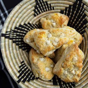 orange scones with white chocolate chips in a black patterned basket.