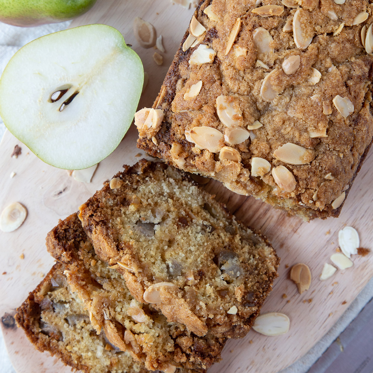 slices of pear bread cut out of a whole loaf, sitting on a wooden board