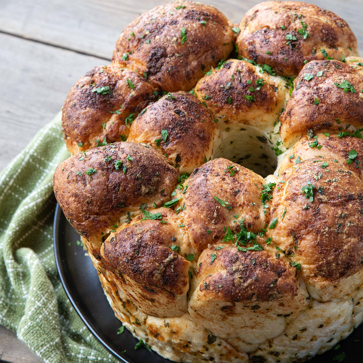 pull apart garlic bread on a green tea towel