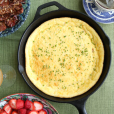 cast iron skillet with spoon bread on a green tablecloth