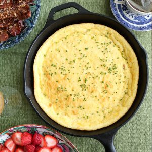 cast iron skillet with spoon bread on a green tablecloth