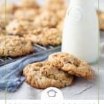 corn flake cookies on a white table with a glass of milk and a blue tea towel.