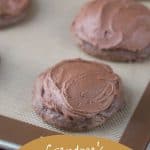 chocolate cookies with chocolate frosting on a silicone baking mat.