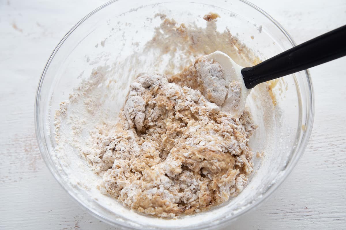 apple muffin batter in a glass bowl with a spatula sticking out.