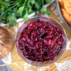 cranberry sauce in a purple glass dish sitting on a Thanksgiving table.