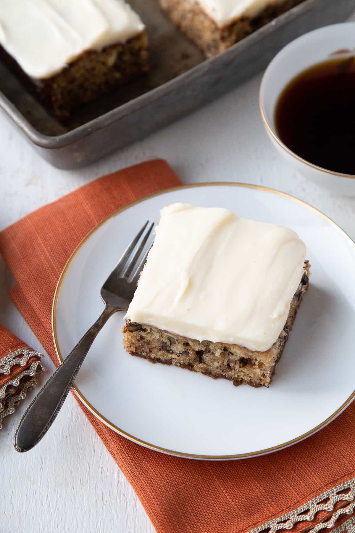 slice of old fashioned banana cake on a white plate with a fork.