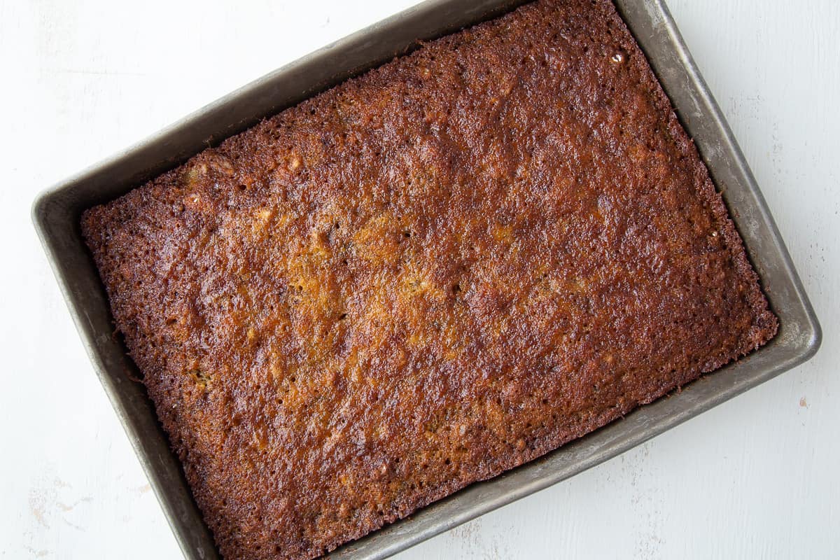 baked banana cake in a metal 13x9 inch pan on a white table.