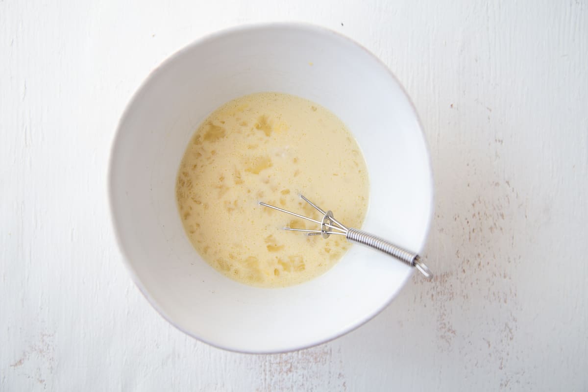 egg mixture in a white bowl with a whisk in it.