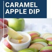 hand dipping an apple slice into caramel dip on a platter surrounded by apple slices.