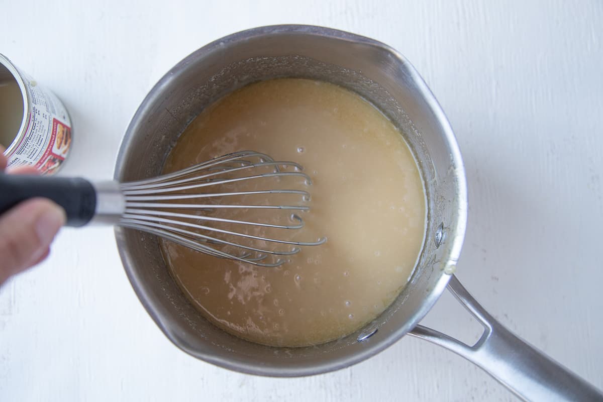 hand whisking caramel dip in a saucepan.