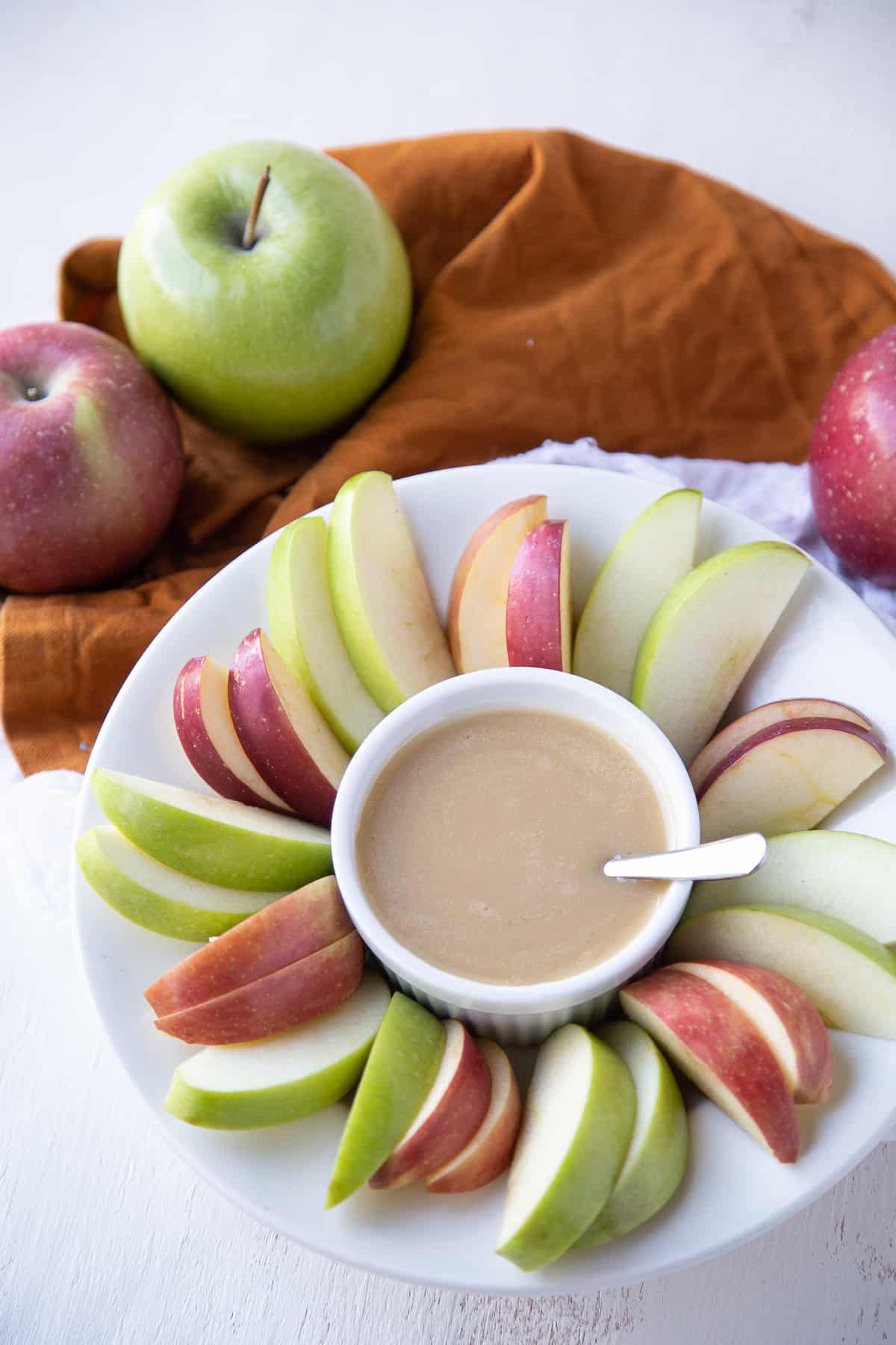 caramel apple dip and apple slices on a round plate.