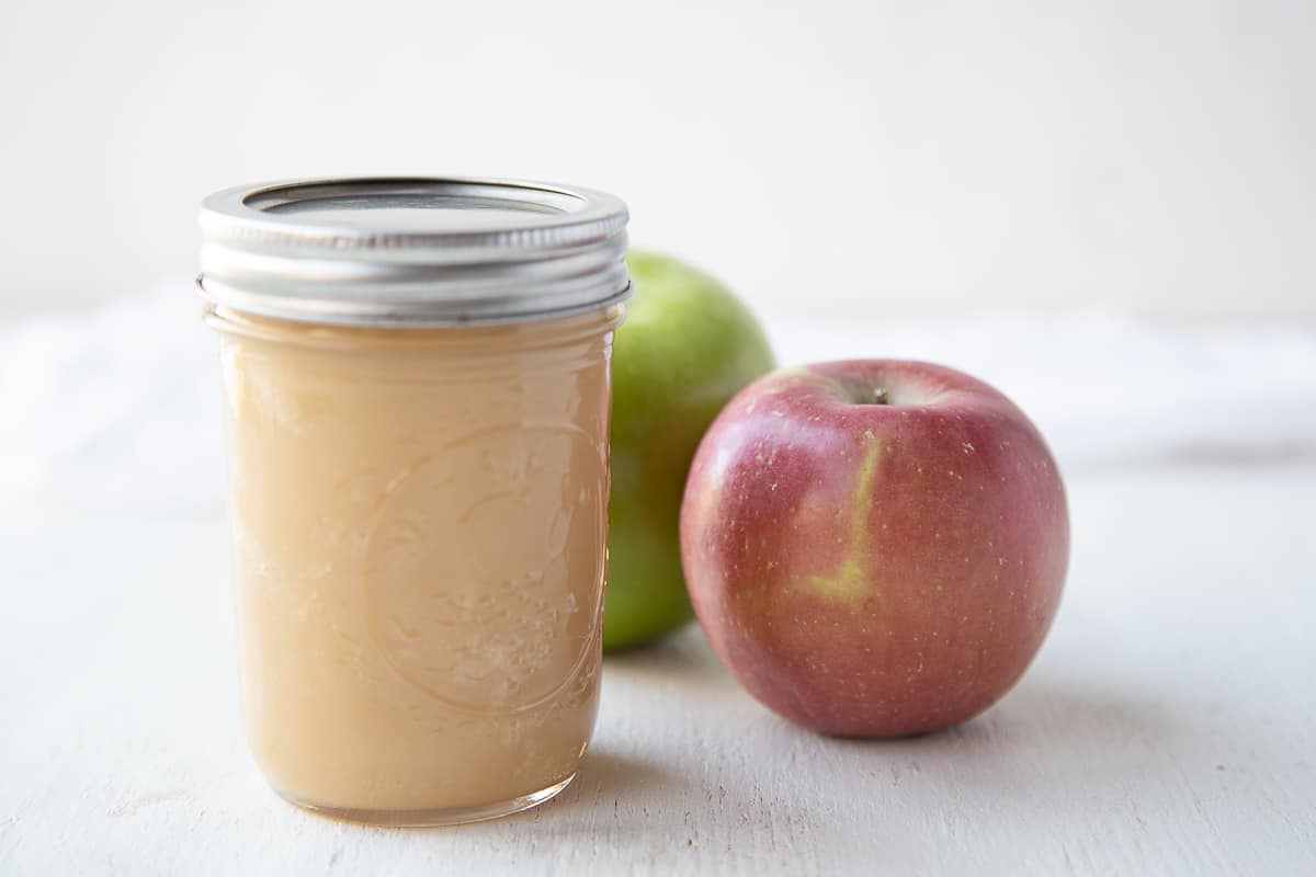mason jar of apple dip and apples on a white table.