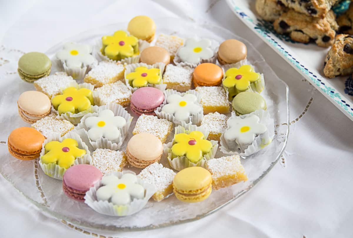 dessert platter with colorful desserts including lemon bars and mini flower shaped cakes.