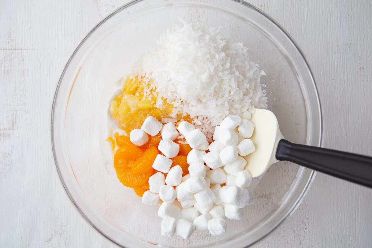 ingredients for 5 cup salad in a glass bowl with a spatula.